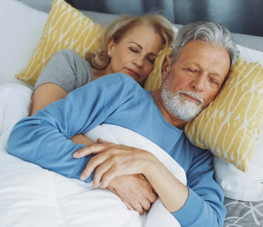 A couple is sleeping soundly together in bed.
